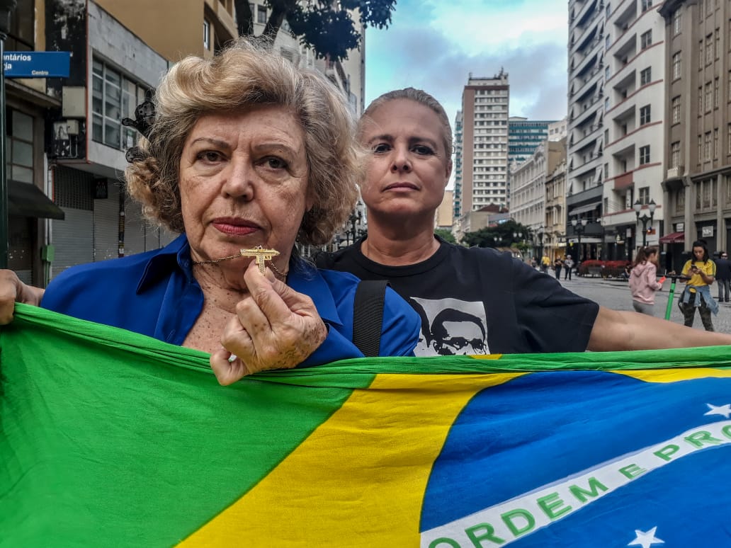 Manifestação pedindo intervenção militar no STF – Supremo Tribunal Federal – reuniu uma dúzia de pessoas em Curitiba neste domingo. Uma das manifestantes, esta senhora só aceitou ser fotografada desde que pudesse exibir o pingente que carrega no pescoço, preso a um cordão: a miniatura dourada de uma submetralhadora Uzi. (Foto Eduardo Matysiak) Manifestação pedindo intervenção militar no STF – Supremo Tribunal Federal – reuniu uma dúzia de pessoas em Curitiba neste domingo. Uma das manifestantes, esta senhora só aceitou ser fotografada desde que pudesse exibir o pingente que carrega no pescoço, preso a um cordão: a miniatura dourada de uma submetralhadora Uzi. (Foto Eduardo Matysiak)